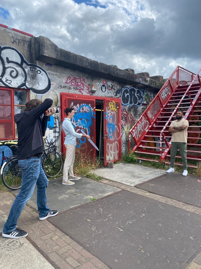 This image showcases a public open-air setting with employees posing at an industrial location, while a photographer from Bakkerito Photography captures the atmosphere. 