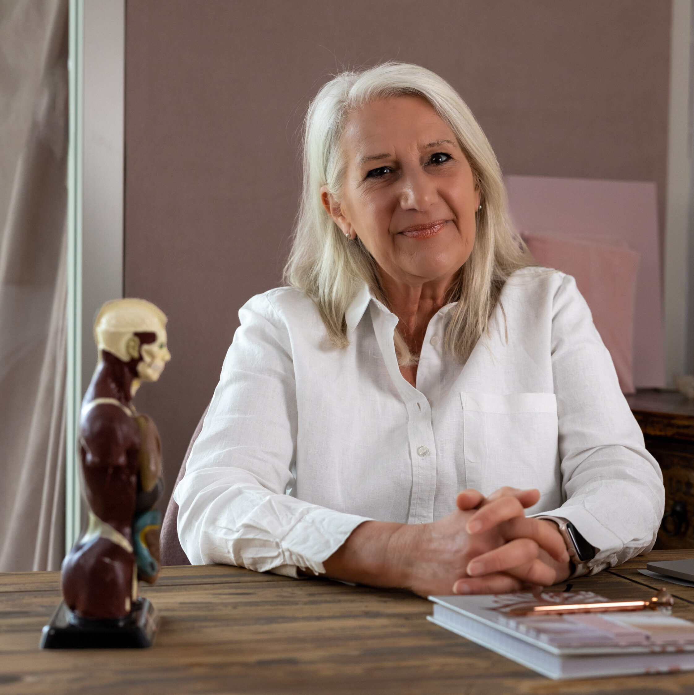 Hier zit Helene in haar praktijkruimte waar ze de behandelsessies doet met haar patienten. Op de voorgrond staat een anatomisch model.